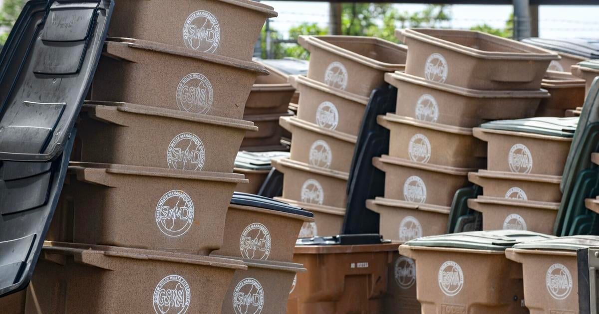 Stacked cardboard boxes with white circular emblems loaded in a vehicle cargo area.
